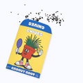 A package of Groovy Root Chives seeds shown on a light gray background with a few black chive seeds scattered above. The package is yellow with blue borders, featuring a cartoon red potted chive character.