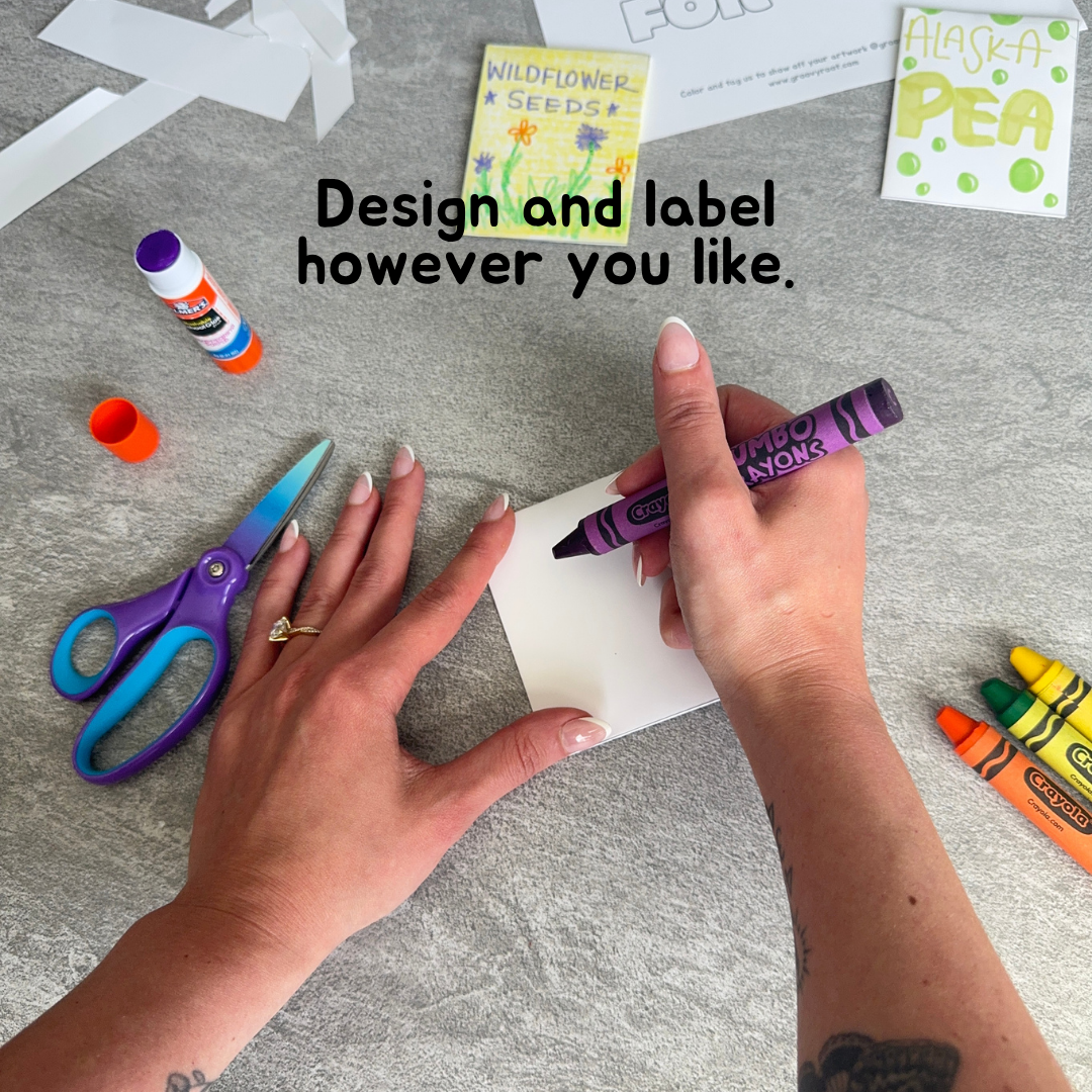 Person holding a purple crayon with text 'Design and label however you like' on a gray surface with craft supplies.