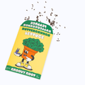 A seed packet for Groovy Root Buttercrunch Lettuce, featuring a yellow background, a green banner, and a cartoon carrot character holding a purple butterfly. Brown lettuce leaves are shown scattered above the packet on a white background.