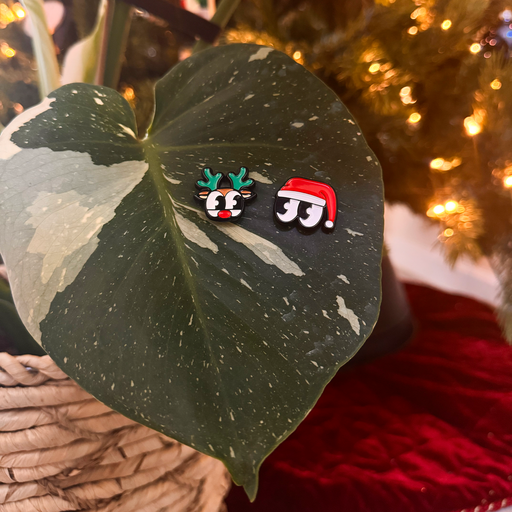 Two Christmas-themed magnets on a leaf with a blurred festive background