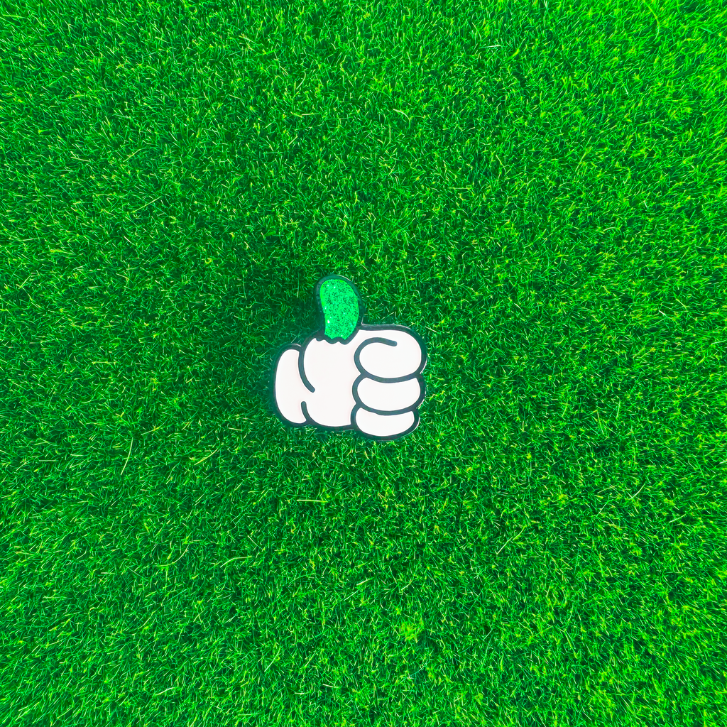 White cartoon hand with a glittery green thumb on a green textured background