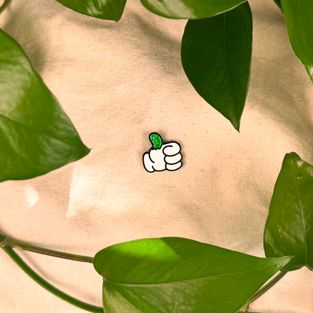 Small white cartoon character with green leaves on a beige background surrounded by green leaves.