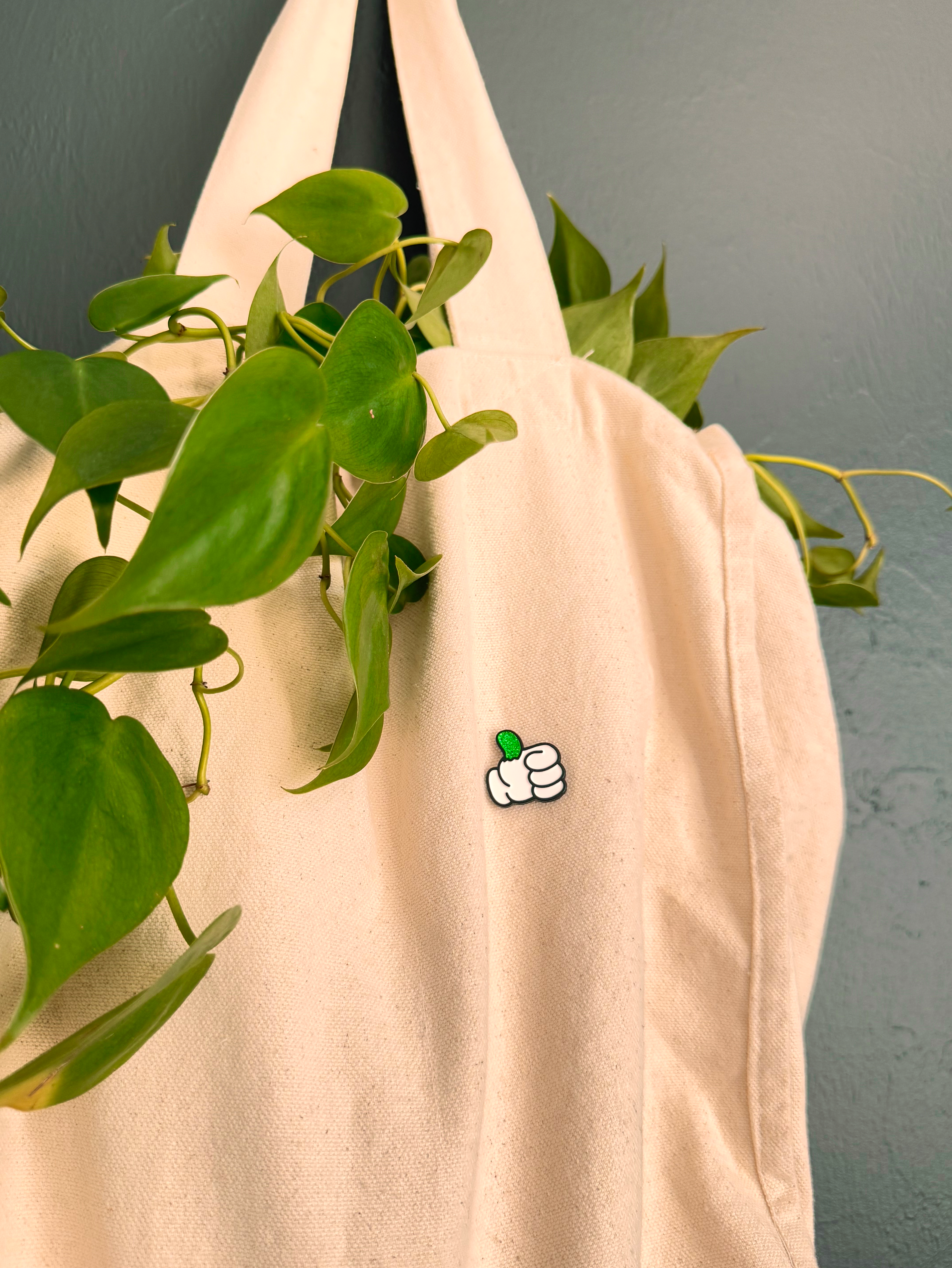 Beige fabric with a small green and white design, hanging plants in the background