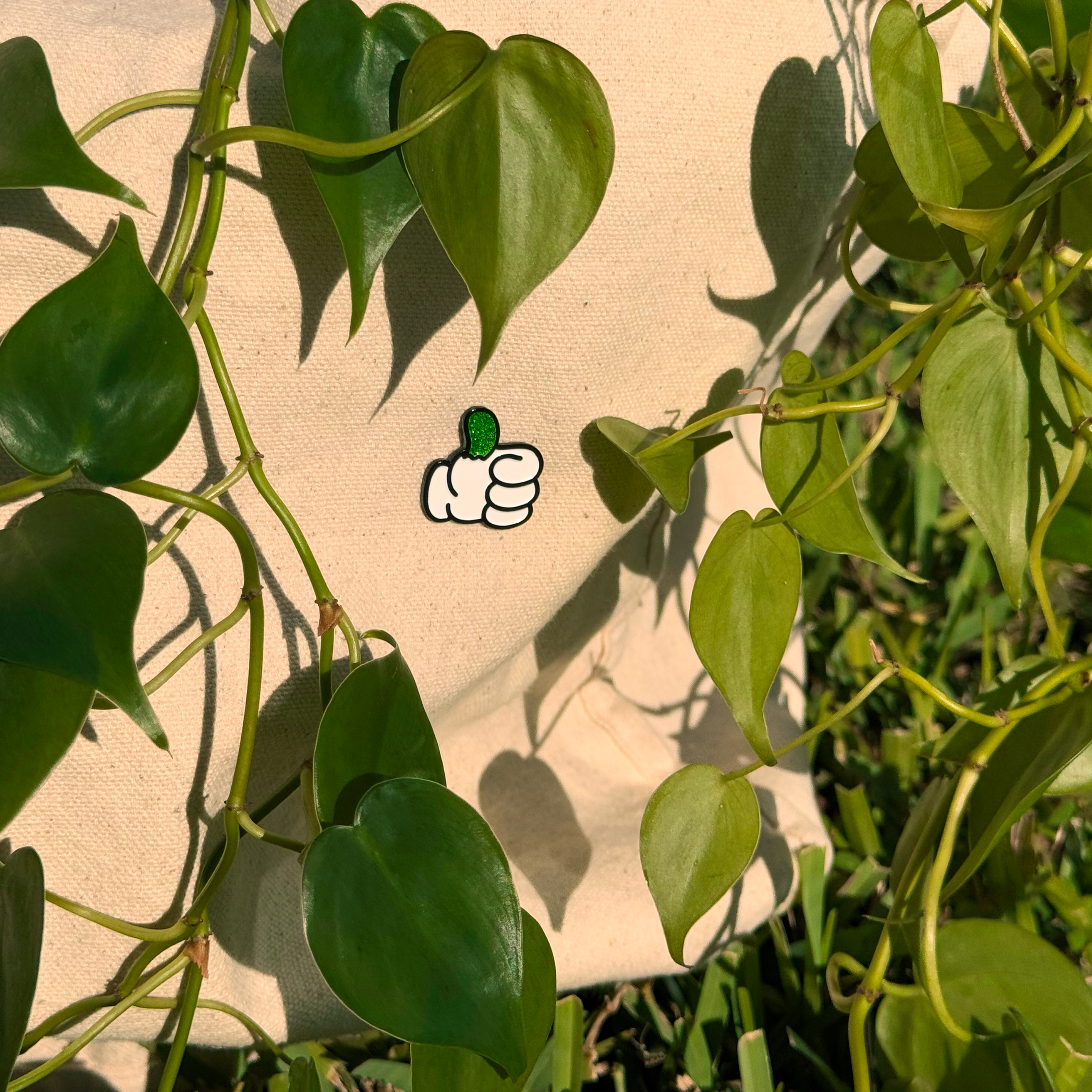 Green leaves with a white icon resembling a hand giving a thumbs-up on a beige background