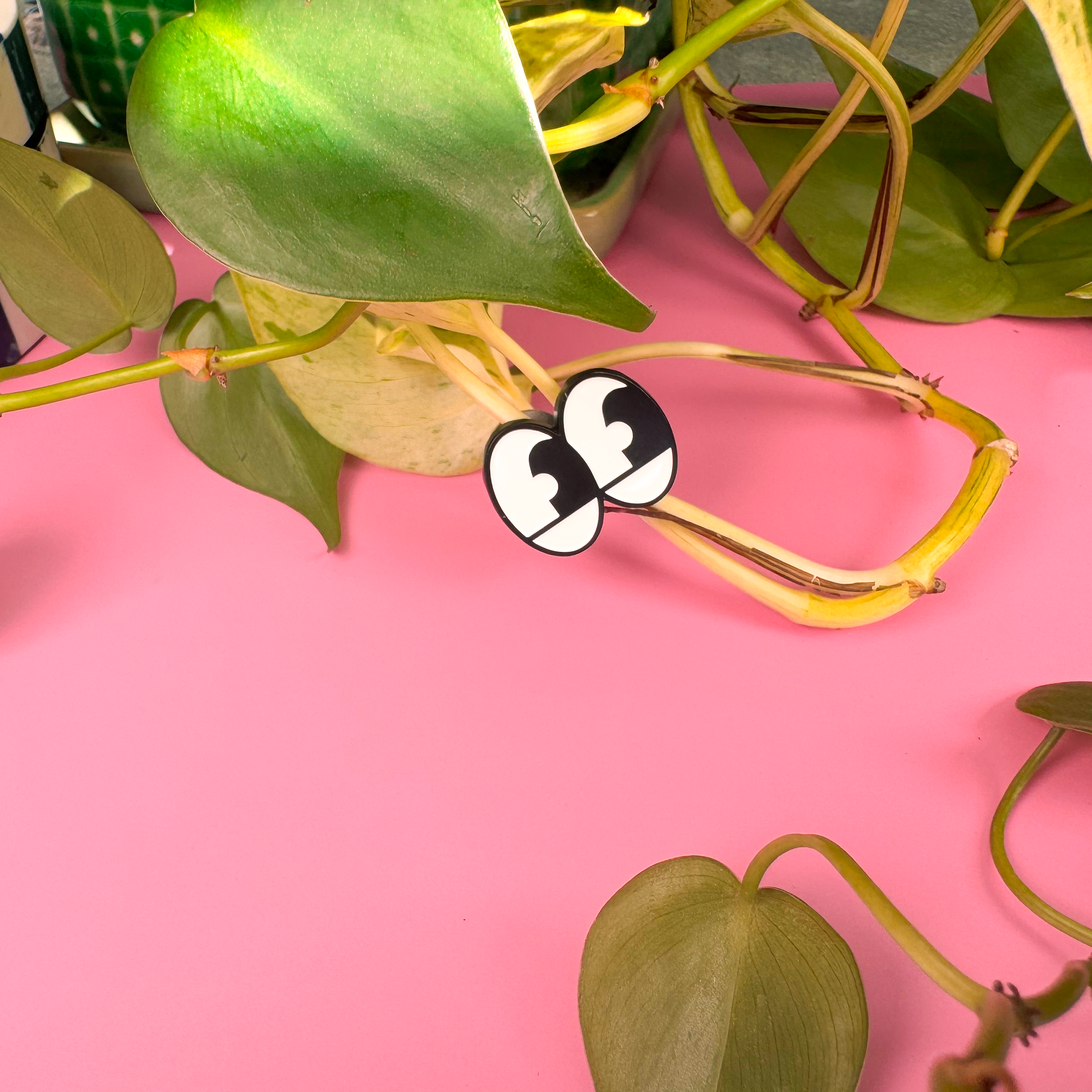 Green leaves on a pink background with a checkered object partially visible