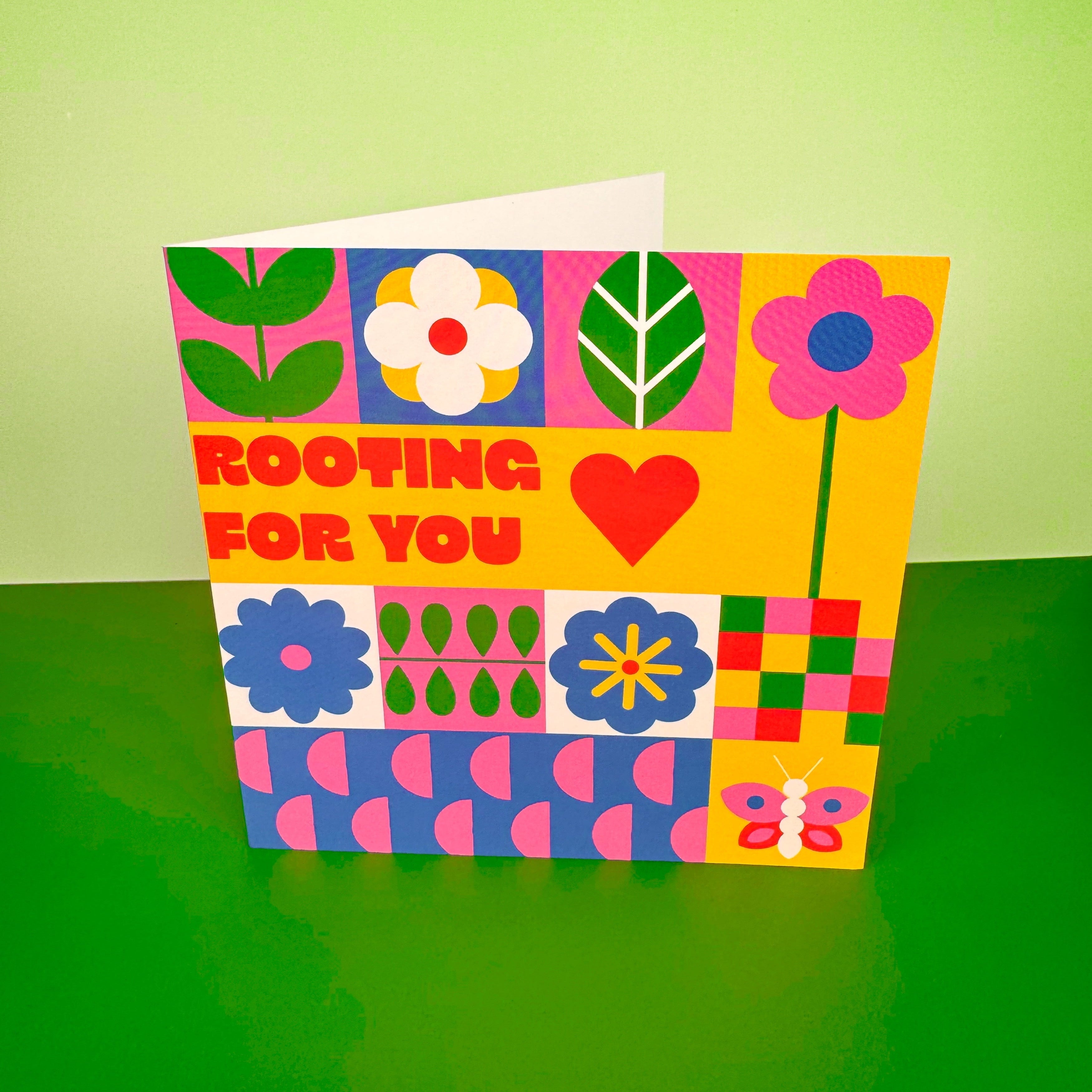 Colorful card with floral patterns and text 'Rooting for you' on a green background