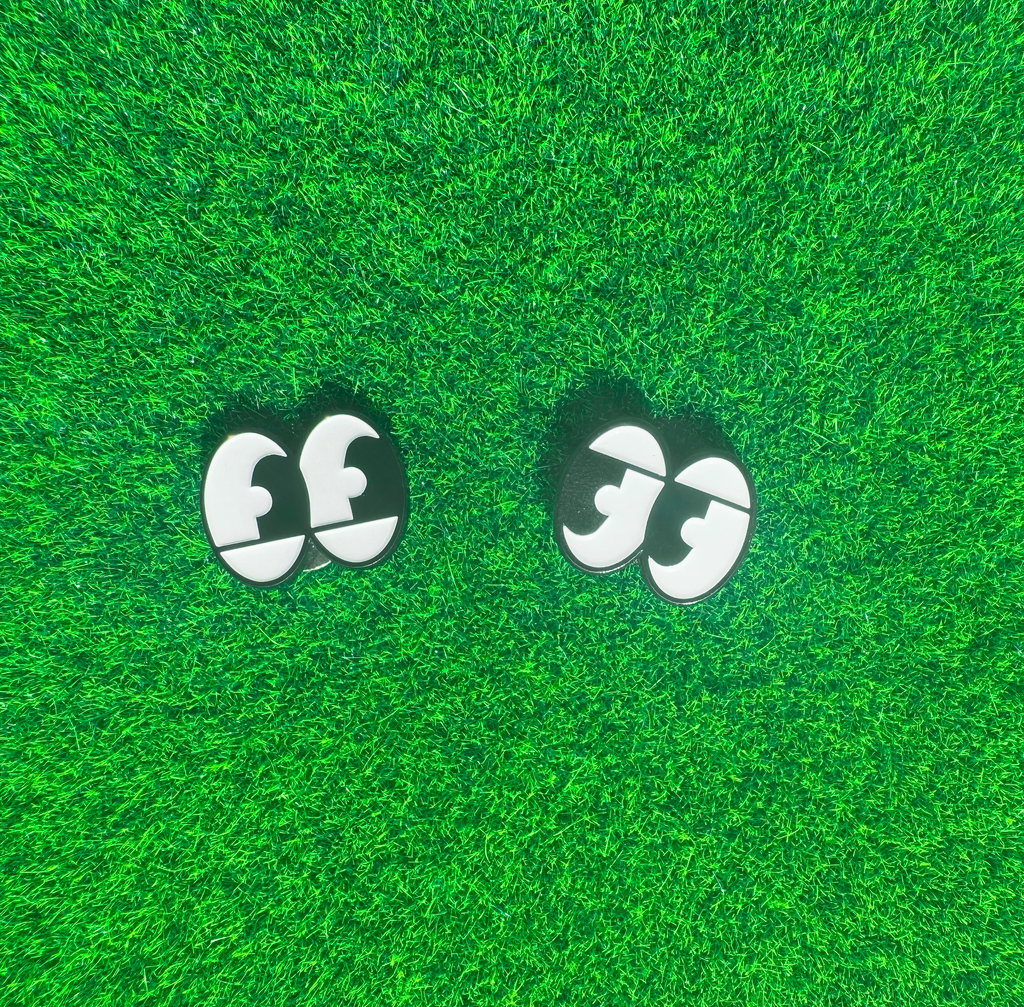 Pair of black and white cartoon eyes on a green textured surface