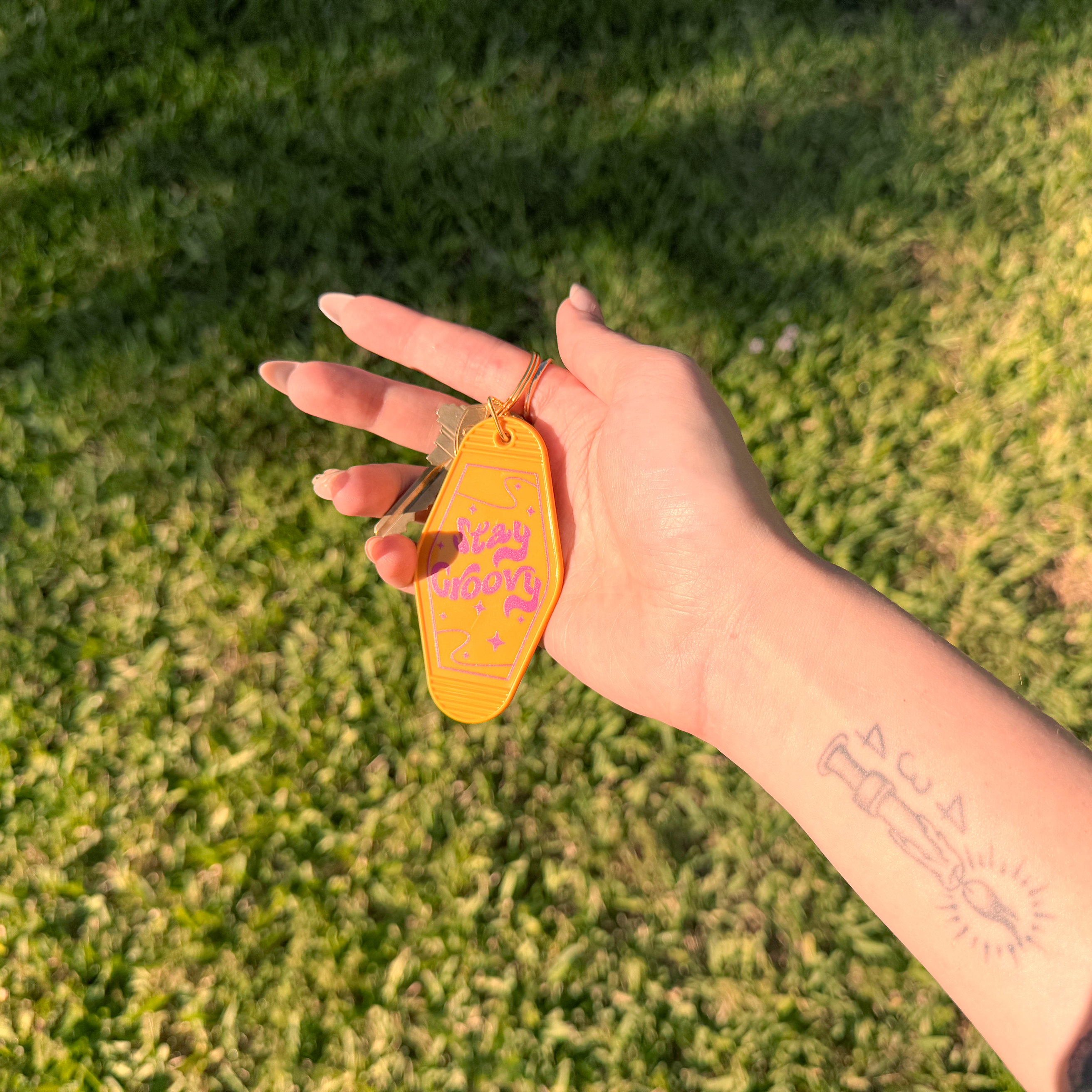 Hand holding a yellow tag with text against a grassy background
