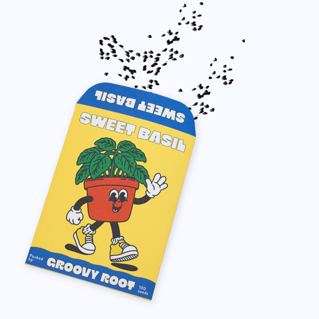 A package of Groovy Root Sweet Basil seeds shown on a light gray background, with black seed particles illustrated floating above it. The package is yellow with blue borders and features a cartoon potted basil plant.